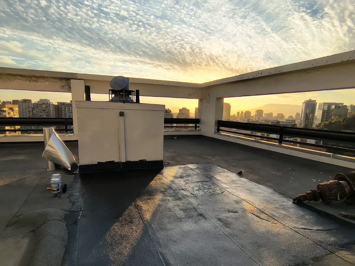 Azotea de edificio cubierta con imprimante asfáltico al atardecer, antes de colocar la membrana