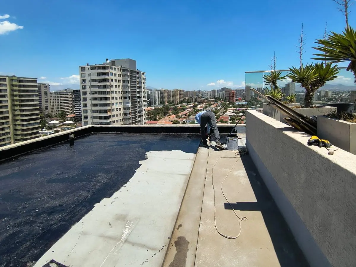 Azotea de un edificio de departamentos con la capa asfáltica avanzando a lo largo del pretil