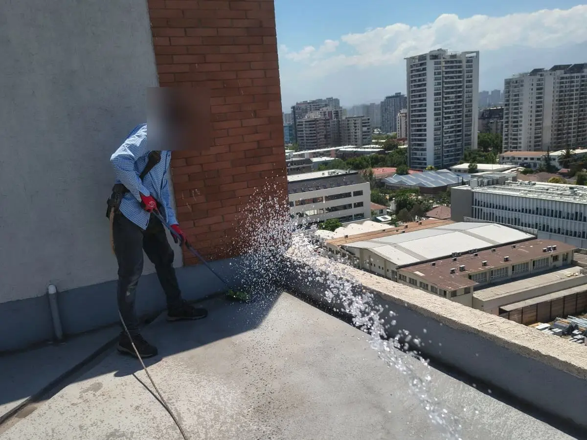 Especialista limpiando con hidrolavado la azotea de un edificio de departamentos