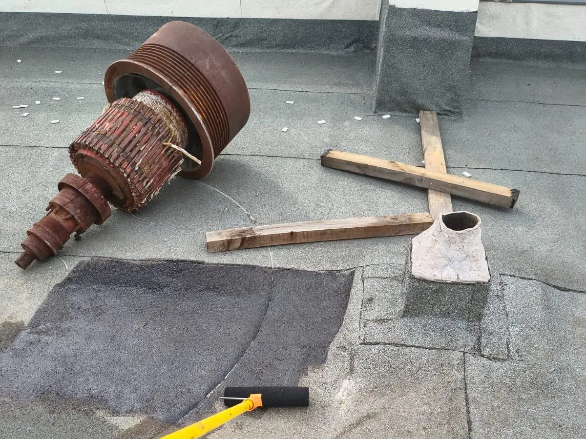 Sector de una azotea con imprimante aplicado junto a la base de un ducto, al lado de piezas retiradas de un extractor